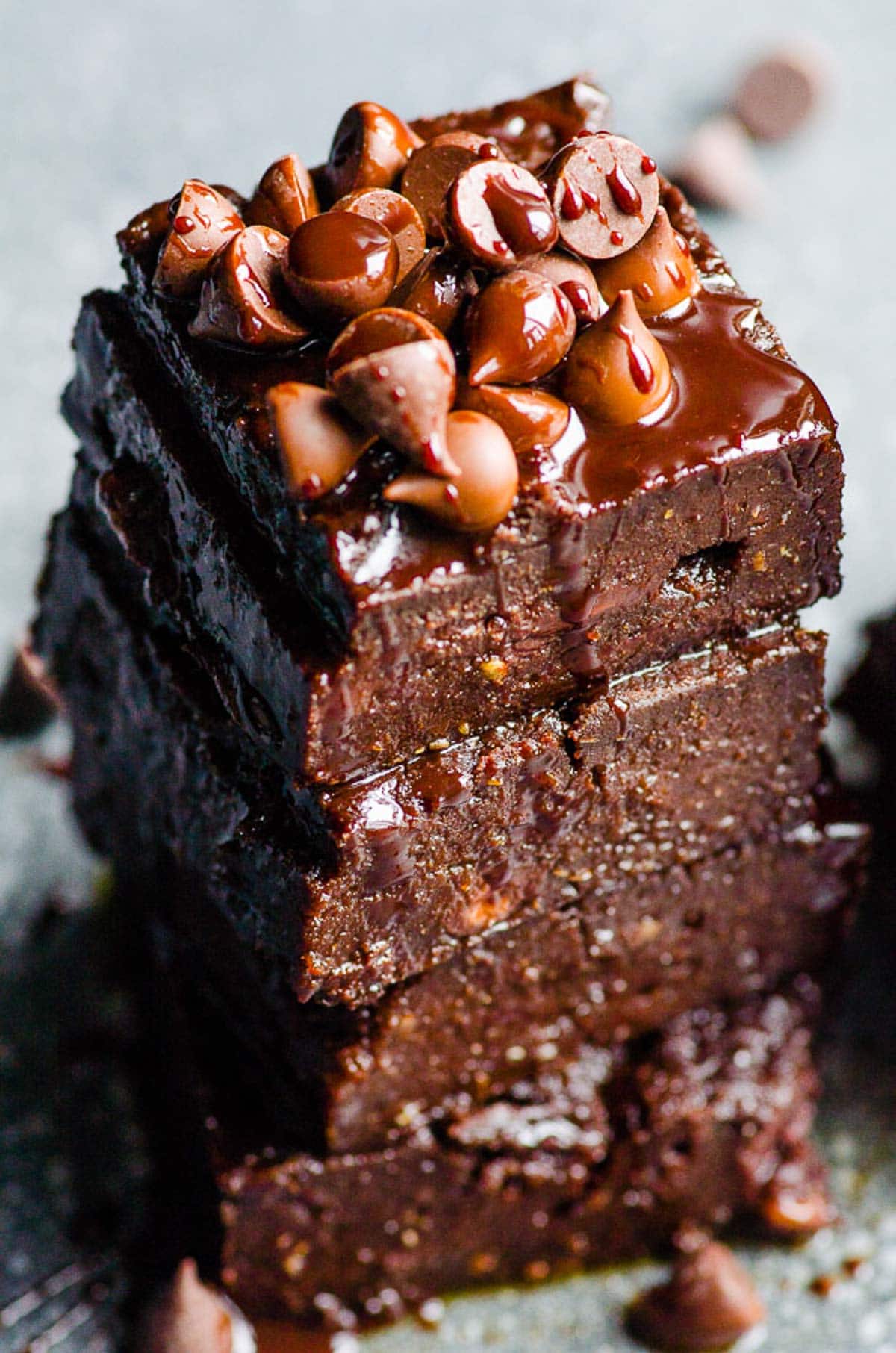 Healthy pumpkin brownies stack with chocolate chips and sauce on top.