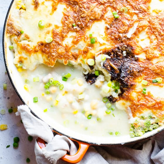 Shepherd's pie with cauliflower in large skillet with towel wrapped around handle.