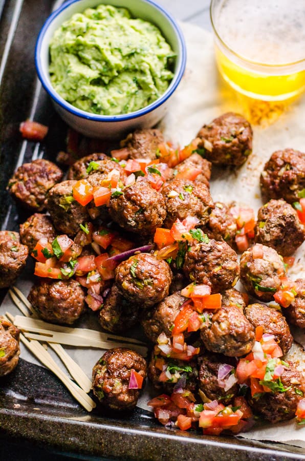 Mexican meatballs on parchment lined pan with guac and beer. 