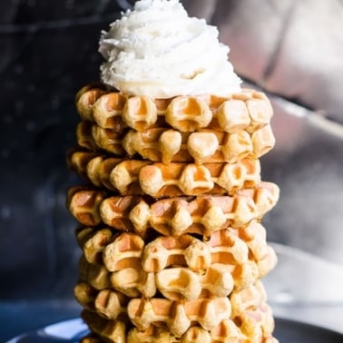 A stack of protein waffles recipe with whipped topping.