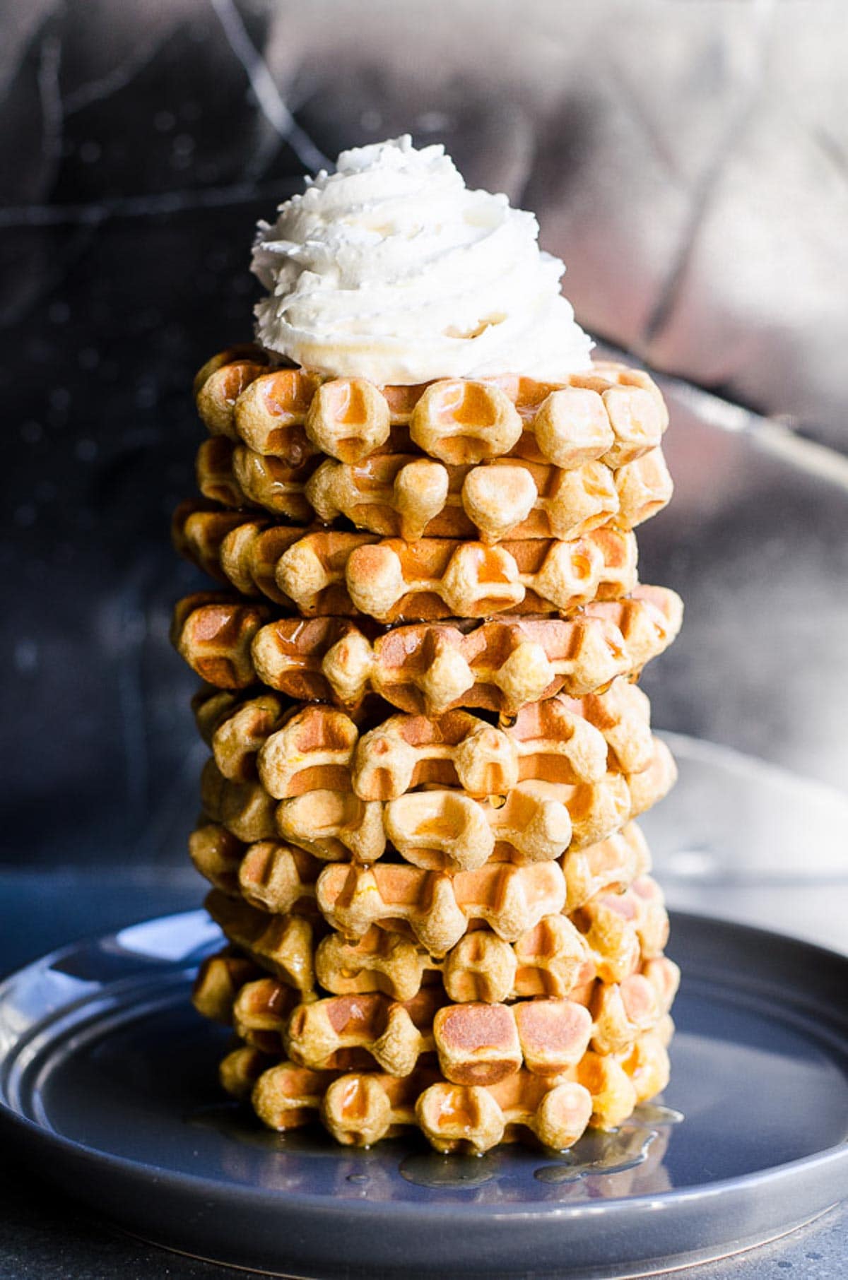 A high stack of protein waffles topped with whipped cream.