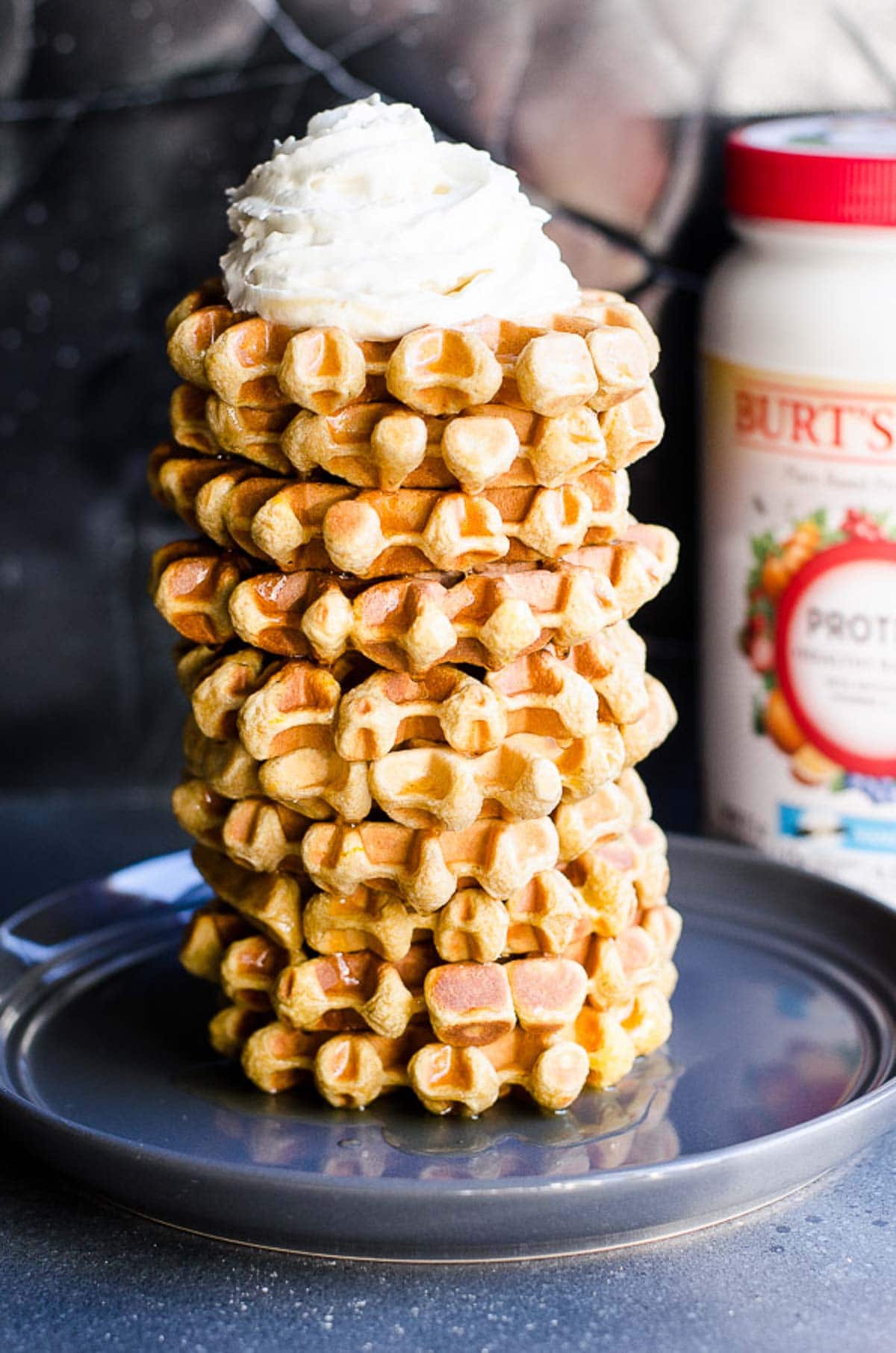 Stack of protein waffles with a canister of protein powder in background.