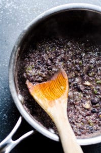 black beans in a pot with a wooden spoon