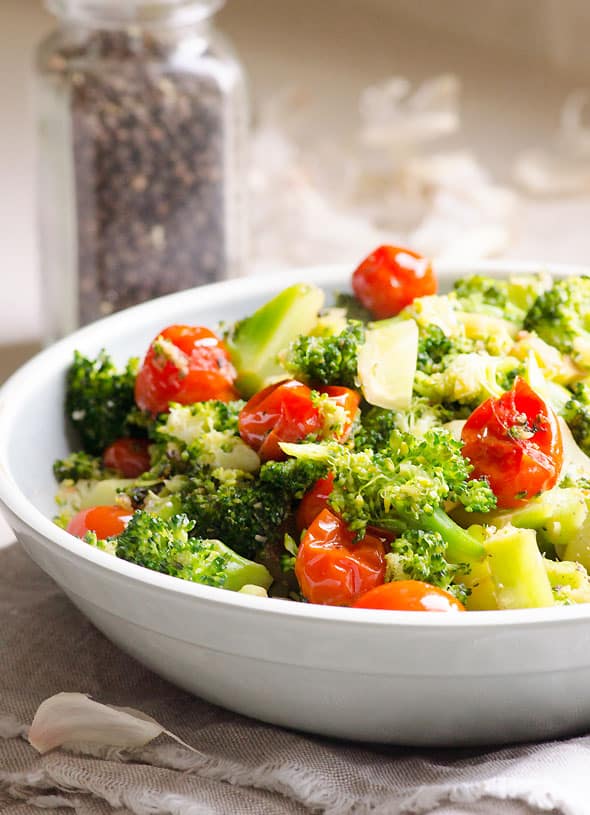 Broccoli with tomatoes in a white bowl.