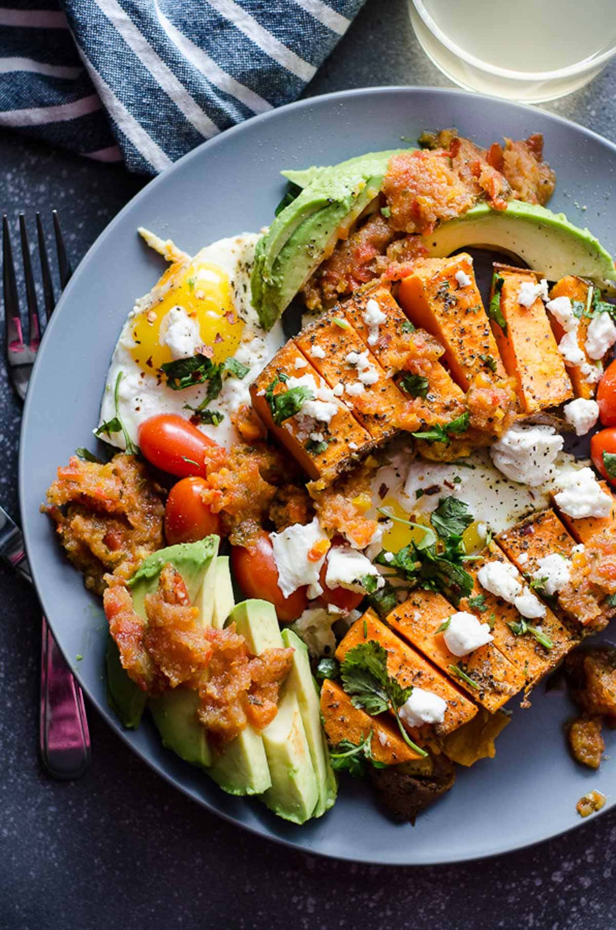 Sweet potato and eggs on a plate with avocado and salsa.