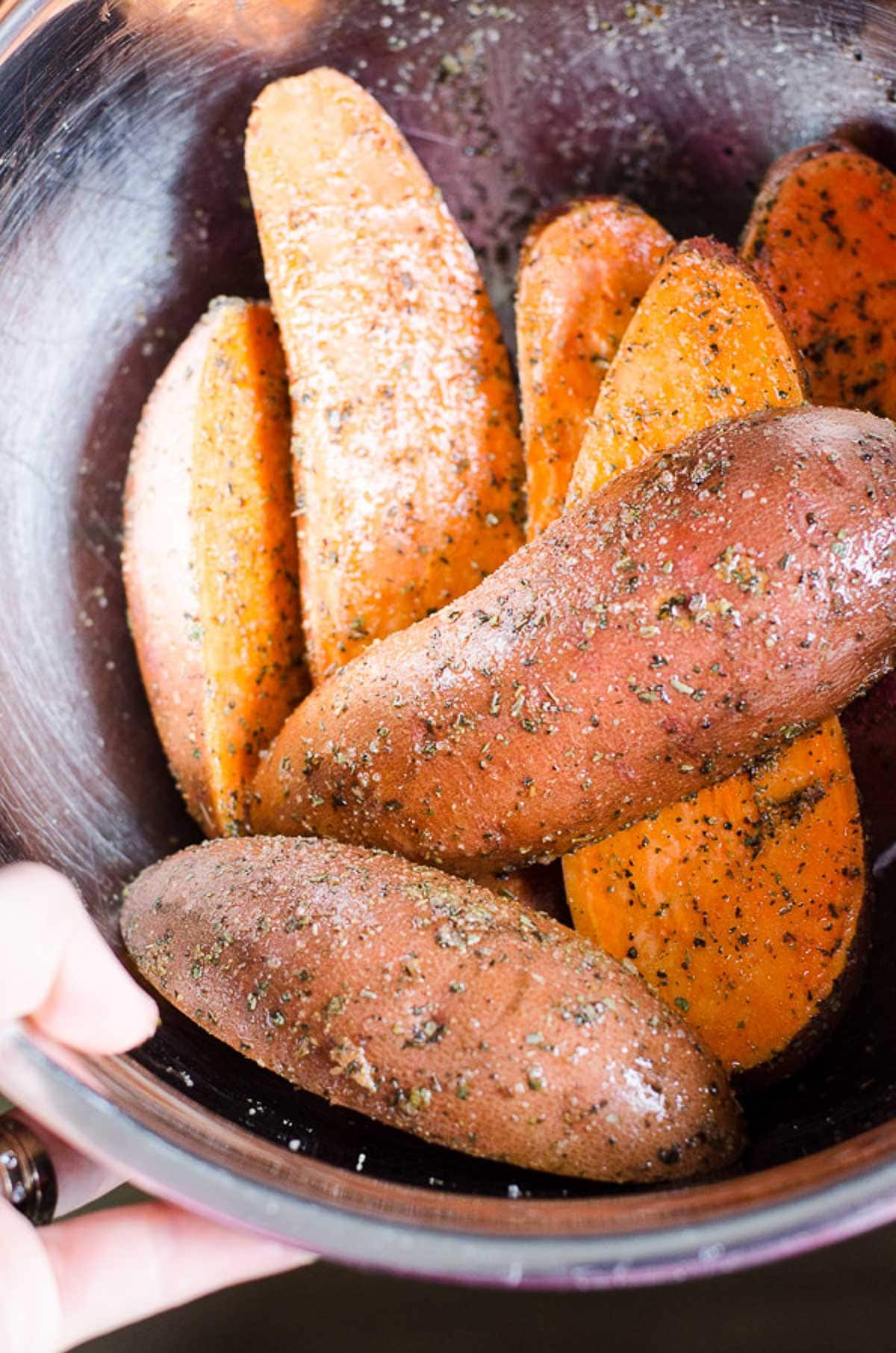 Cut sweet potatoes with oil and seasonings in a bowl.