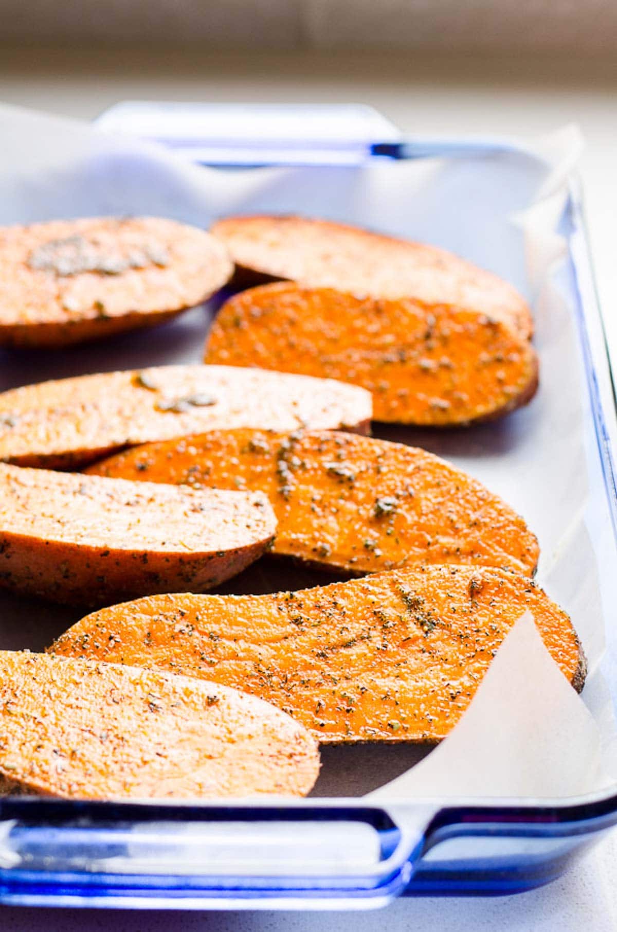 Sweet potatoes in baking dish lined with parchment paper.