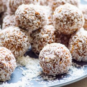 No bake protein balls in coconut flakes on blue plate.