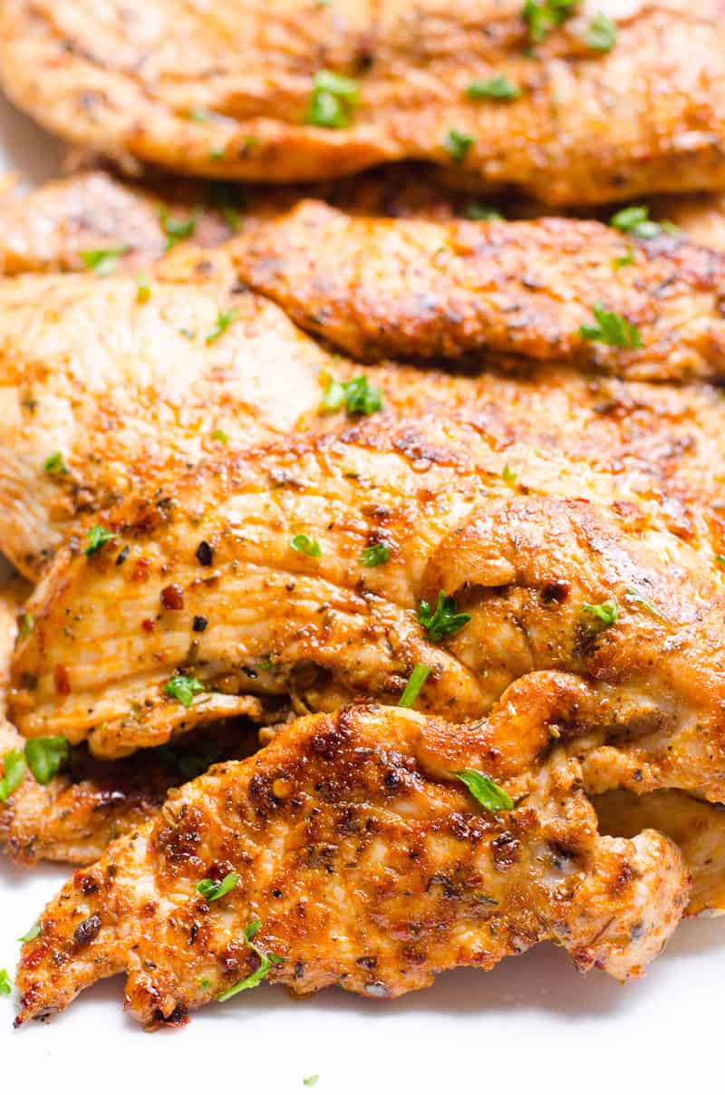 Cajun chicken breasts garnished with parsley and served on white plate.