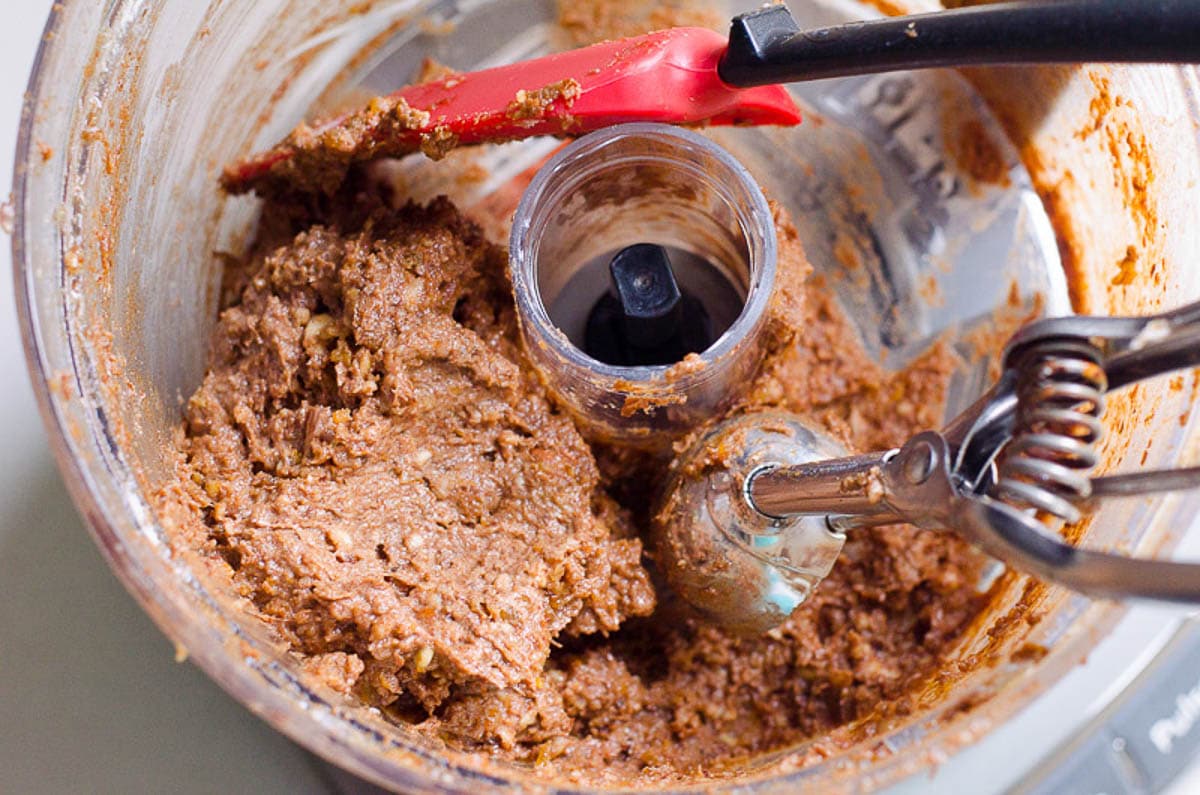 Protein balls dough in processor with spatula and scoop.