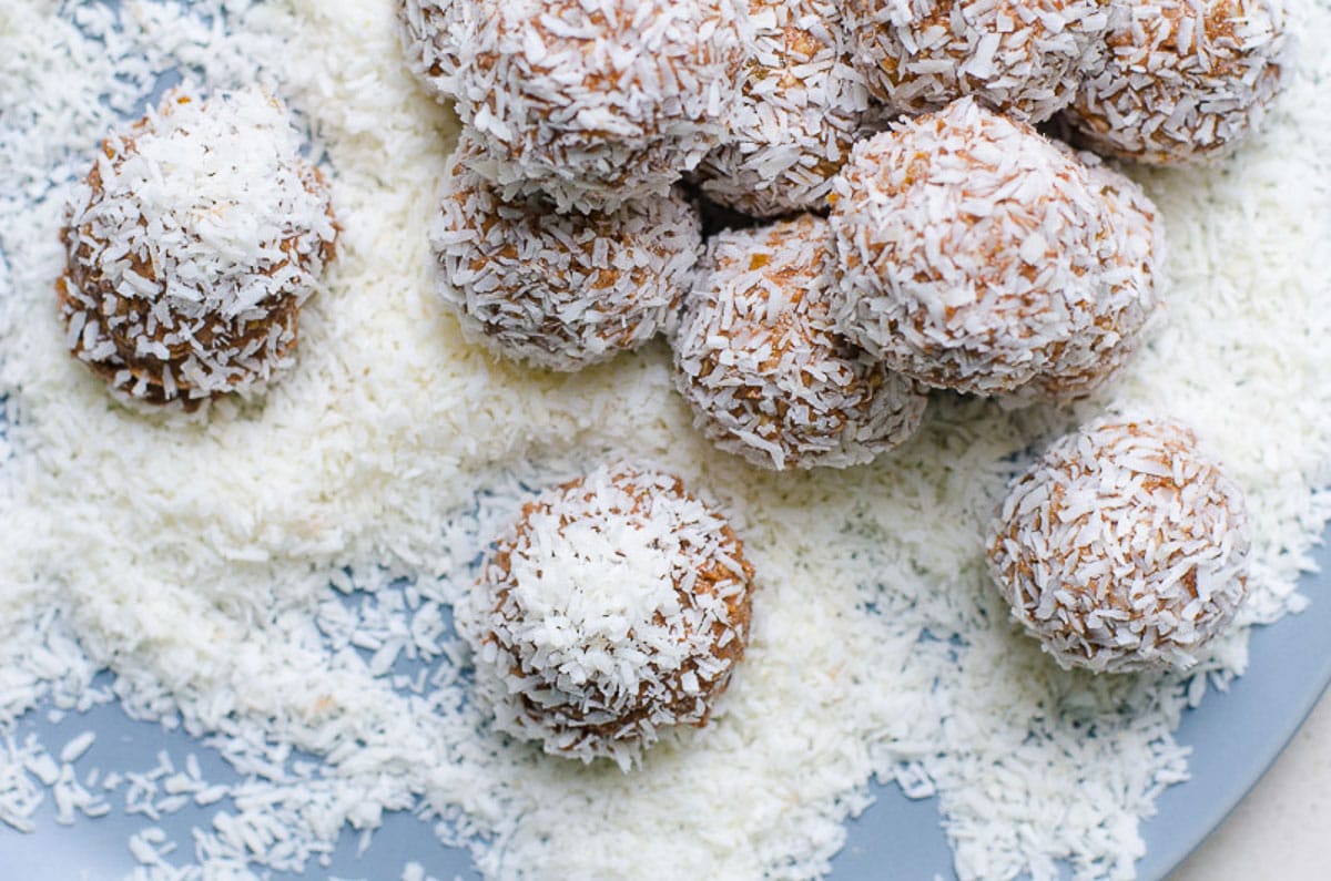 Energy bites on a plate with lots of coconut flakes.