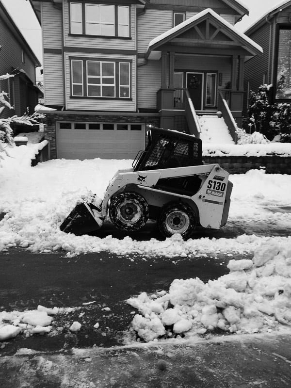 A bobcat clearing the snow from a street. 