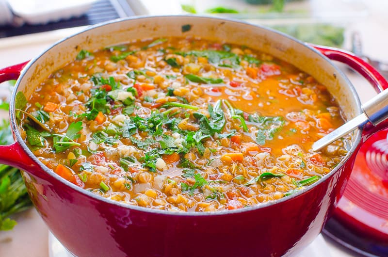 Pot of lentil spinach soup with a ladle.