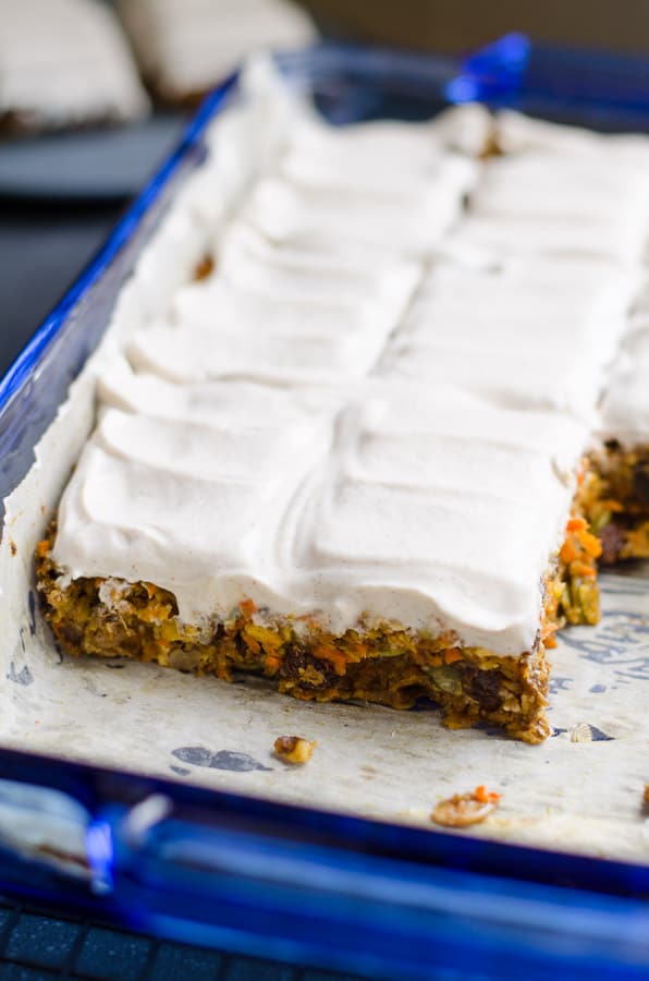 Sliced baked oatmeal bars with frosting in blue baking dish.