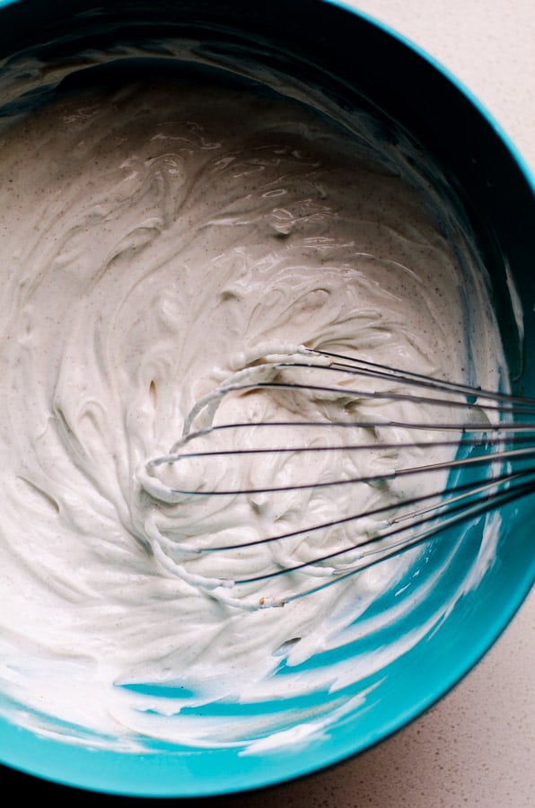 Greek yogurt frosting whisked in blue bowl.