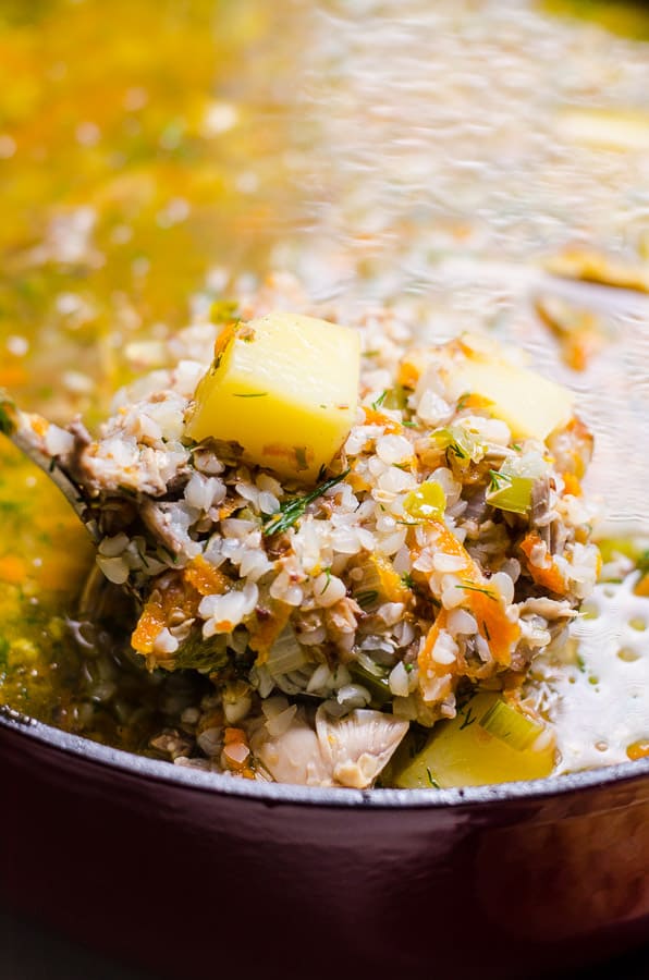 Close up of buckwheat soup with potatoes on a ladle.