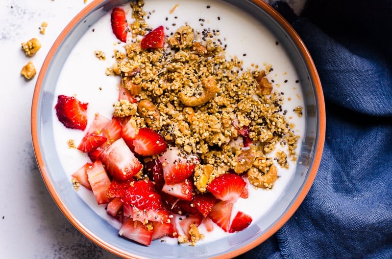 quinoa granola in a bowl of milk and strawberries