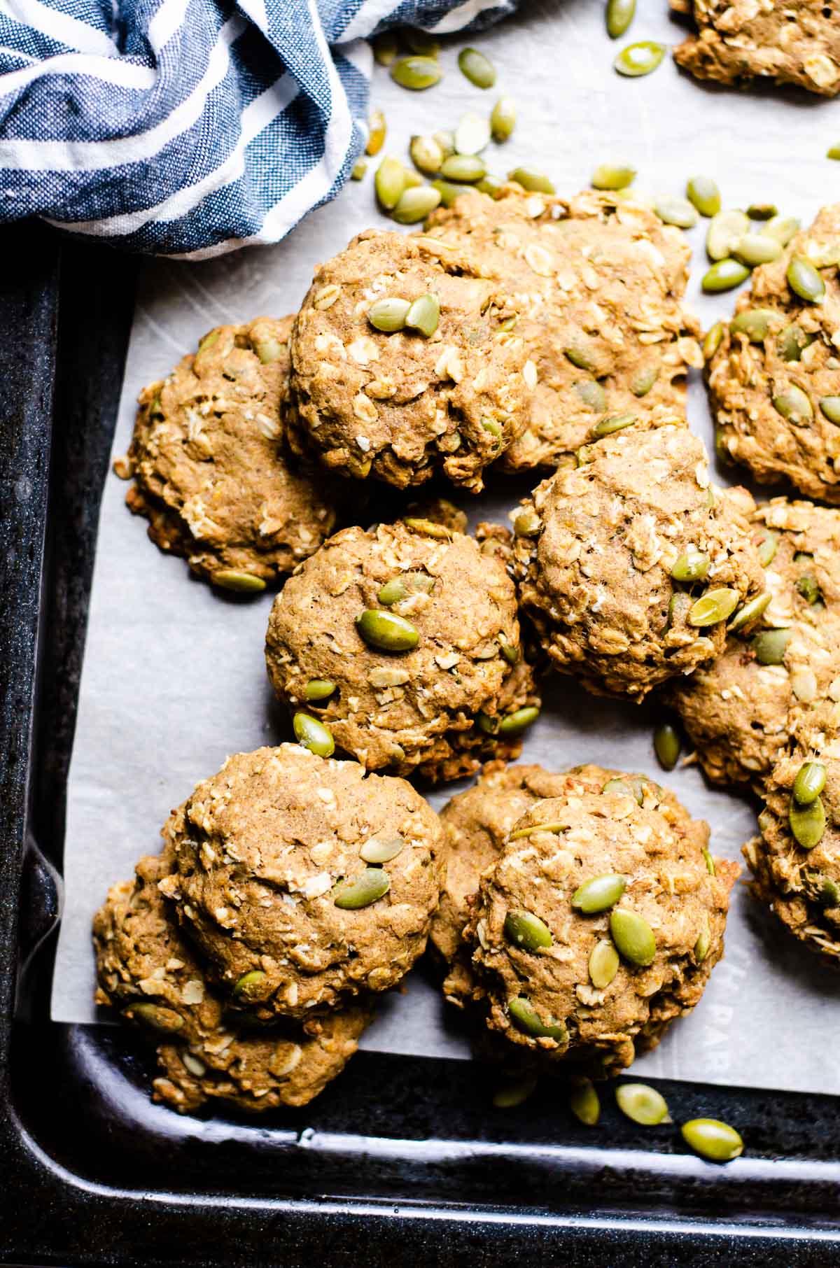 Healthy pumpkin cookies on a baking sheet with pumpkin seeds. Blue white linen towel.