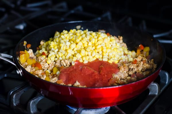 Corn and tomato sauce in red skillet.