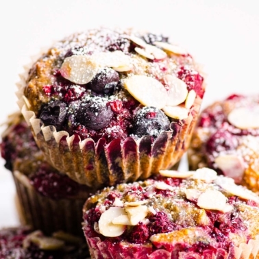Almond muffins with sliced almonds and icing sugar stacked on top of each other.