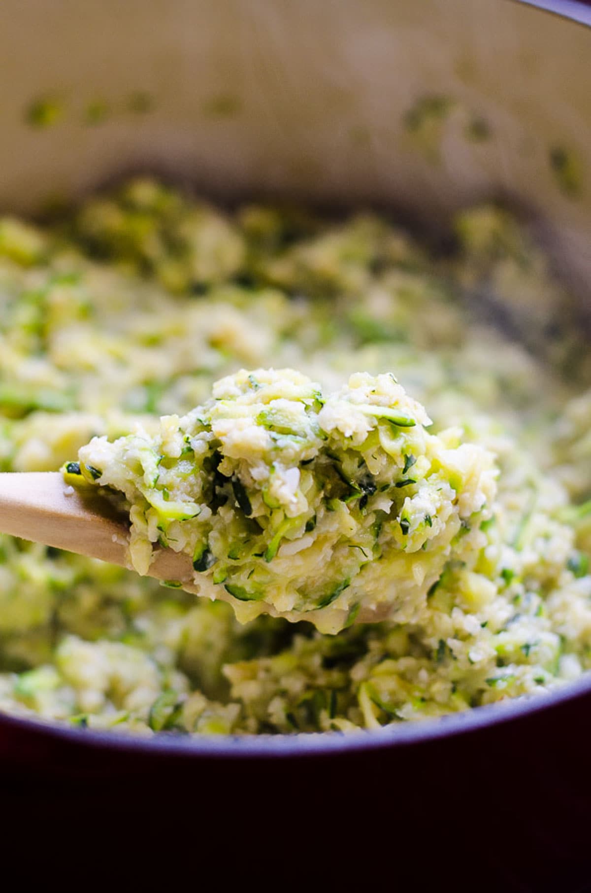 Cheesy cauliflower rice on a wooden spoon.