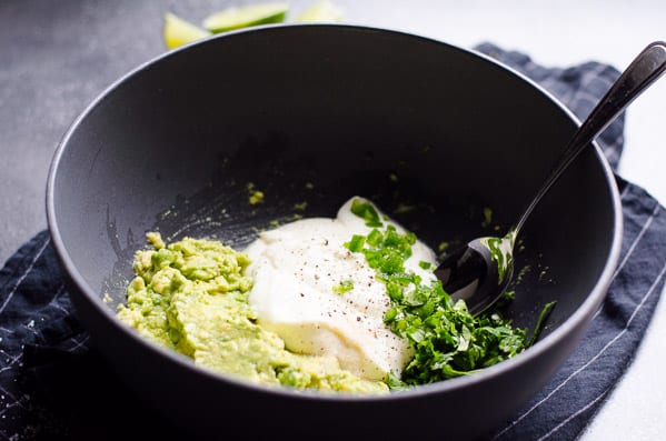 Greek Yogurt Guacamole ingredients in a bowl with a spoon