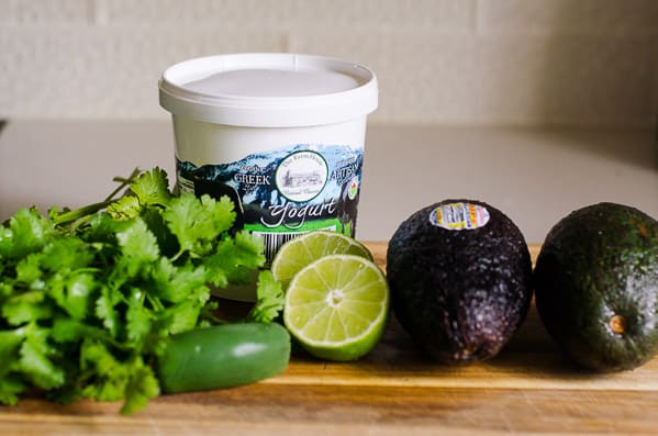 cilantro, avocado, lime and yogurt on a cutting board