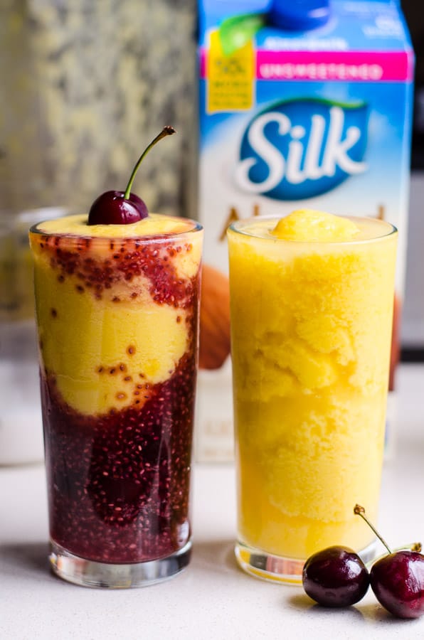 Two kombucha smoothies in tall glasses and fresh cherries.