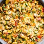 Tex Mex chicken and zucchini recipe with melted cheese and cilantro in blue skillet.