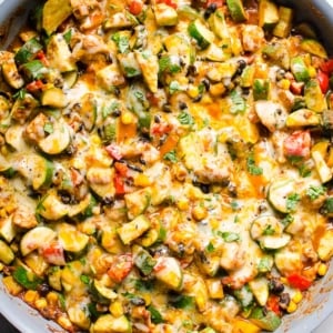 Tex Mex chicken and zucchini with melted cheese and cilantro in blue skillet.
