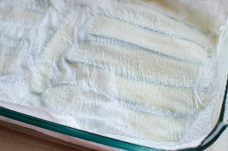 sliced zucchini noodles covered with paper towel to absorb moisture