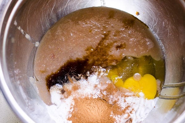 Applesauce, egg, maple syrup, vanilla and baking staples in metal bowl.