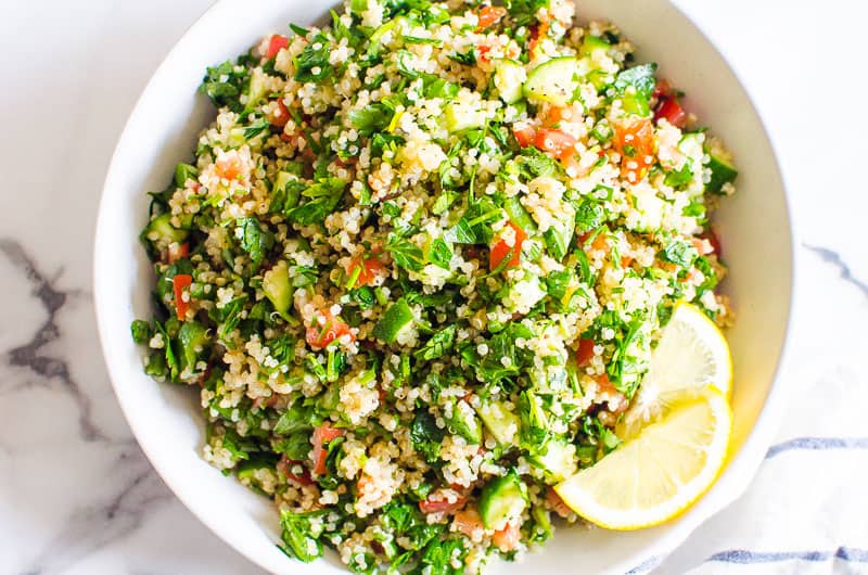 quinoa tabbouleh salad in a white bowl served with lemon slices