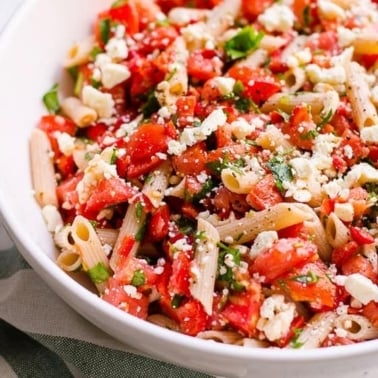 Tomato pasta salad with feta and basil in a bowl.