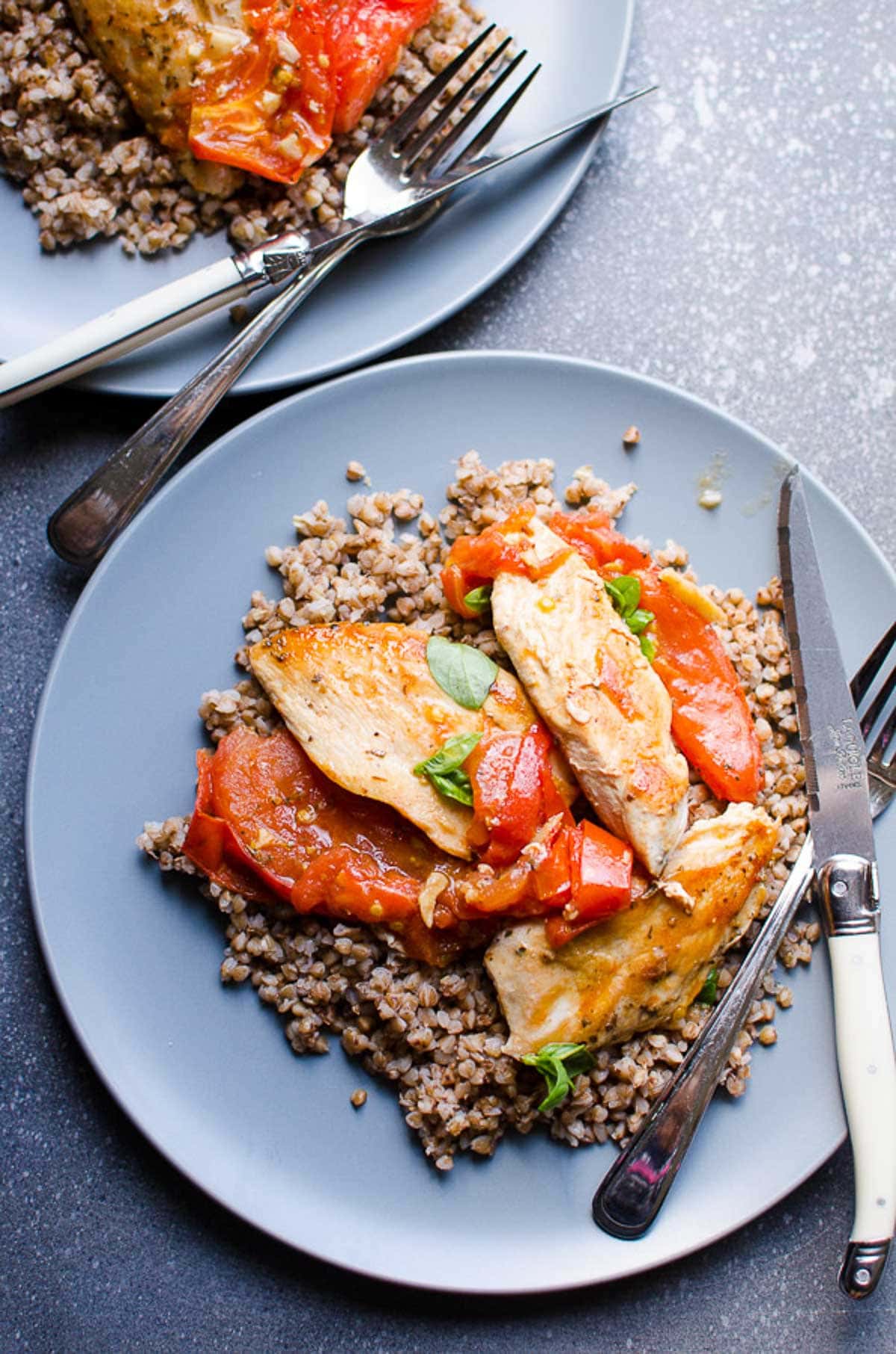 Chicken with tomatoes served with buckwheat on a plate.