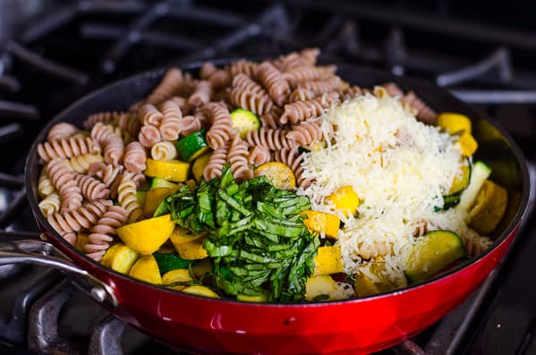 Pasta, zucchini, fresh basil and parmesan cheese in large skillet on stove.