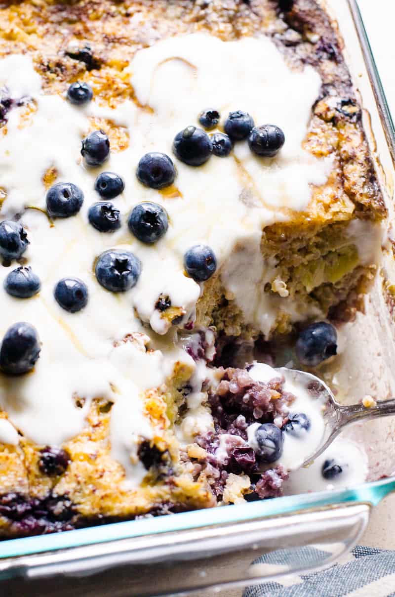 Quinoa breakfast bake with yogurt and blueberries on top served in a baking dish with spoon.