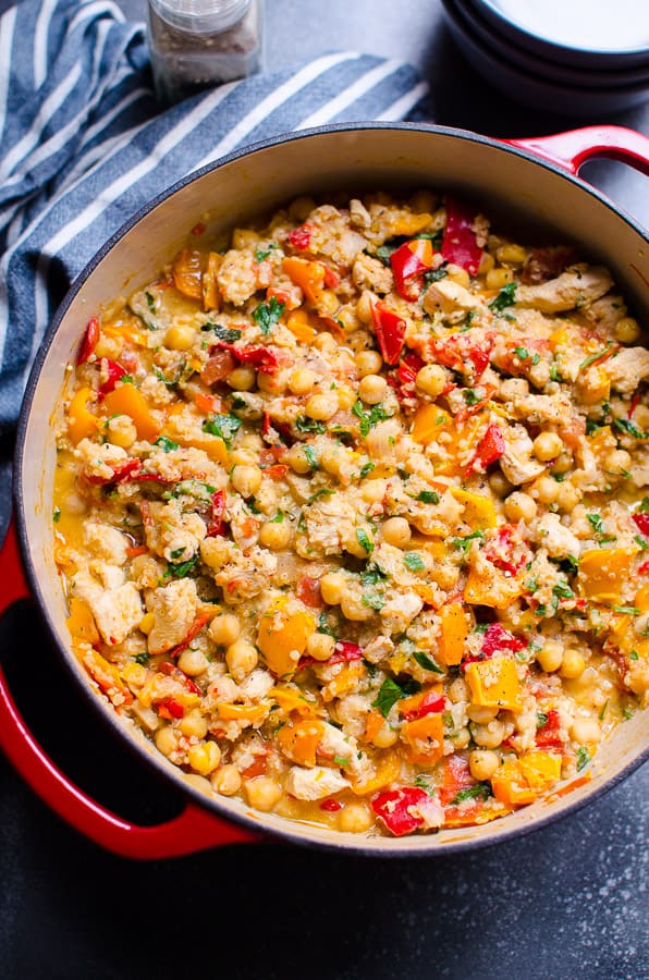 Chicken chickpea stew garnished with parsley in red pot.