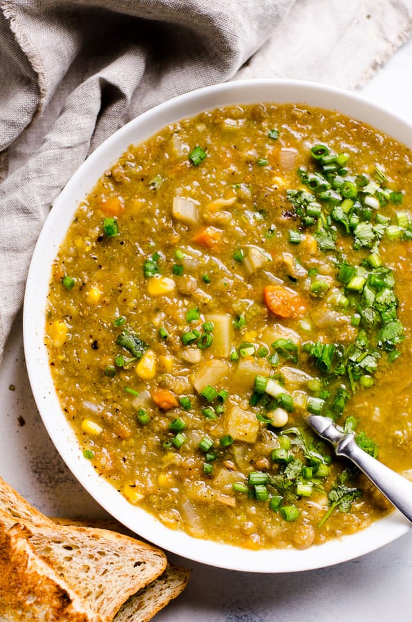 Slow cooker lentil soup in a bowl with whole grain bread for serving.