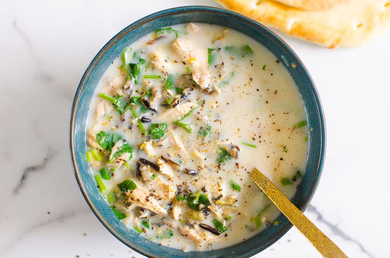 blue bowl of healthy chicken wild rice soup with a spoon in the bowl