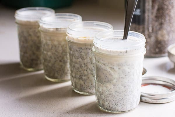 Four mason jars with almond milk and chia seeds.