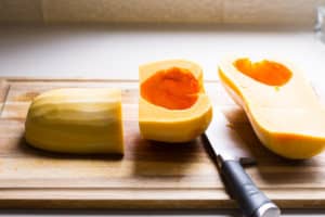 butternut squash on a cutting board cut and peeled with a knife
