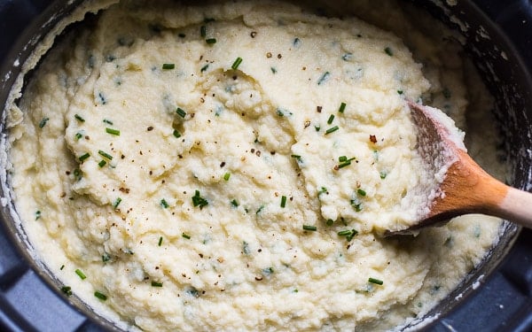 Slow cooker cauliflower mashed potatoes with serving spoon.