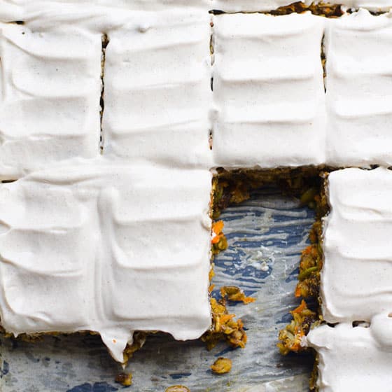 Sliced baked oatmeal bars with Greek yogurt frosting in baking dish.