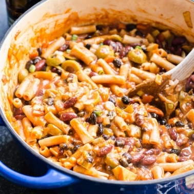 One pot chili mac with beans in blue pot and wooden spoon in it.