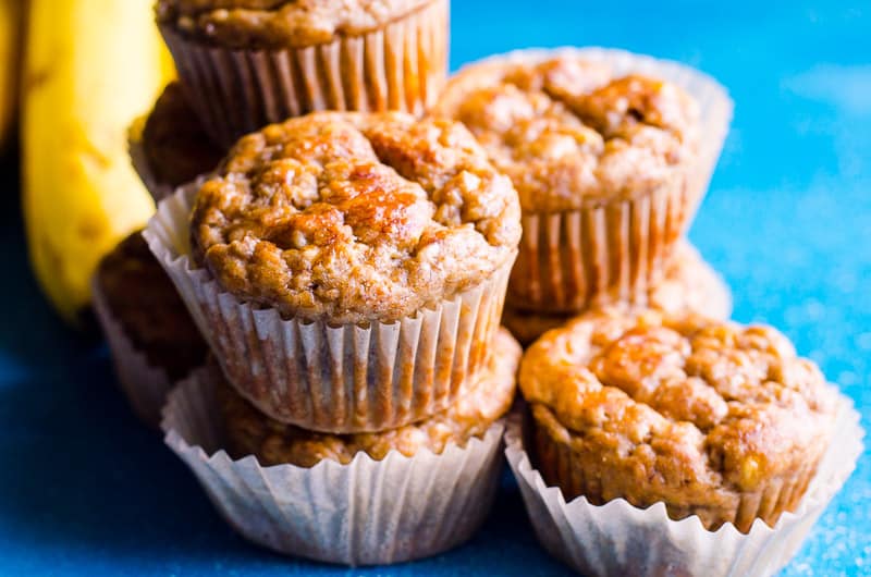 healthy banana muffins stacked on top of each other with bananas