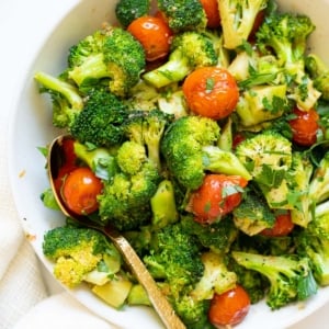 Sauteed broccoli with tomatoes in a bowl with a spoon.