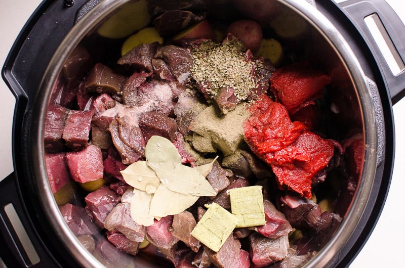 Beef, bay leaves, tomato paste, spices and bouillon cubes in Instant Pot.
