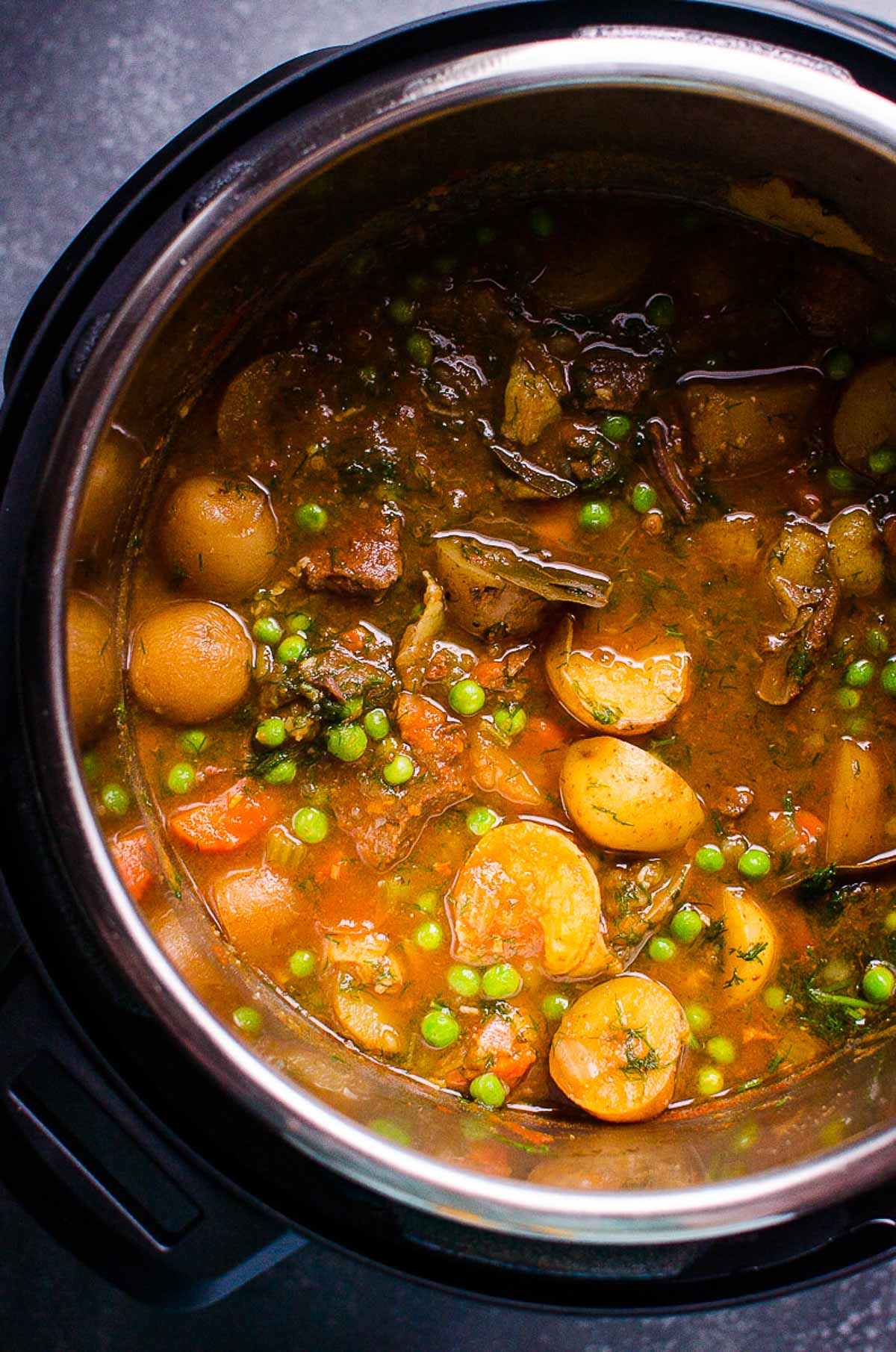 Instant Pot beef stew with peas, dill and carrots in rich broth in the pressure cooker.