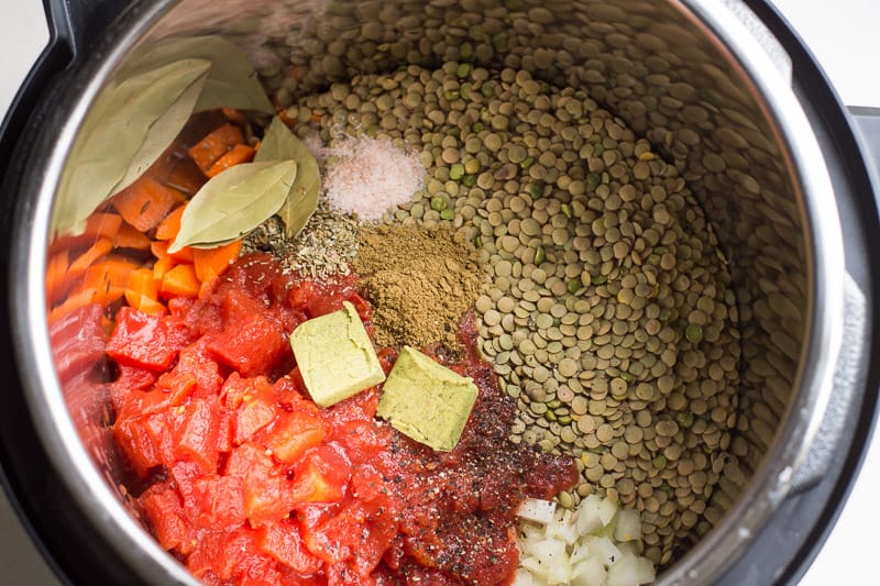 Spices, green lentils, bouillon cubes and diced tomatoes in Instant Pot.
